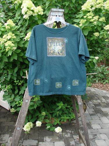 1996 Short Sleeved Promo Tee Old Frenchtown Field Viridian Size 1 displayed on a rustic ladder, featuring a square graphic with sun motifs, showcasing BlueFishFinder's vintage creativity in organic cotton.