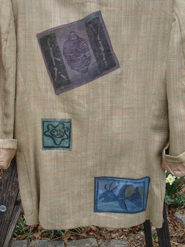 Close-up of the 1994 Patched Blazer Elements Grass Wheat Tweed OSFA, showcasing detailed nature patches, square shoulder pads, and a three-button closure against a light wheaty plaid fabric.