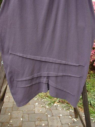 2000 Thermal Awen Skirt Larger Elastic Unpainted Eggplant Size 2 displayed on a wooden railing, featuring a textured, diagonal hemline with directional folds.