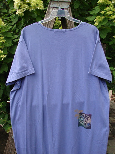 Lavender-purple oversized T-shirt hanging outdoors, featuring a small square graphic, related to the 1997 Aquavella Dress Celtic Trio Skylark Size 2, reflecting Bluefishfinder.com's vintage, expressive style.
