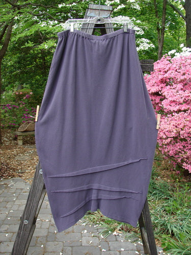 2000 Thermal Awen Skirt Larger Elastic Unpainted Eggplant Size 2 displayed on a wooden rack, showcasing its full elastic waistband, bell shape, and textured diagonal hemline.