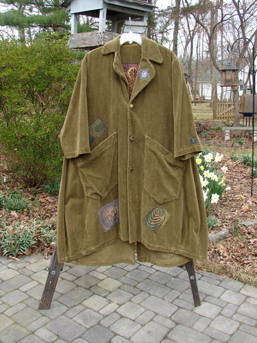 1998 Patched Tapestry Coat Forest Path Glazed Tile OSFA displayed on a rack; features include angular pockets, vintage buttons, and a stand-up collar with detailed patches throughout.