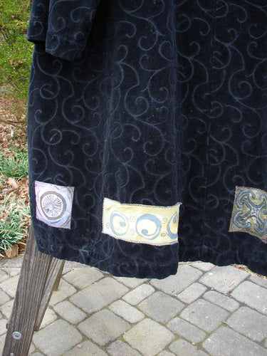 1999 Patched Poet's Coat Holiday Time Black Size 0: Heavyweight textured cotton with vine-patterned pile, colorful patched hem, oversized vintage buttons, wrapped collar, diagonal pockets, varying hemline, tapestry fabric.