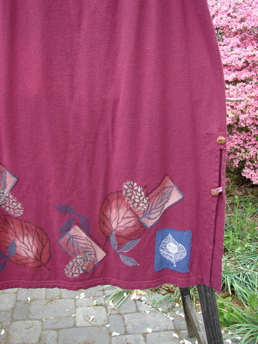 Barclay Panel Nut Button Vented Skirt Oakleaf Madder Size 2, featuring a leaf-themed design around the hemline, dual nut-like buttons, and two tall vented sides, made from medium-weight organic cotton.