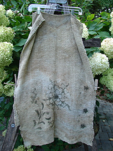 Barclay Crinkle Cotton Scarf in Morning Fern Mottled Wheat, displayed outdoors on a hanger, features a hand-painted floral motif on coarse fabric, embodying BlueFishFinder's unique vintage charm.
