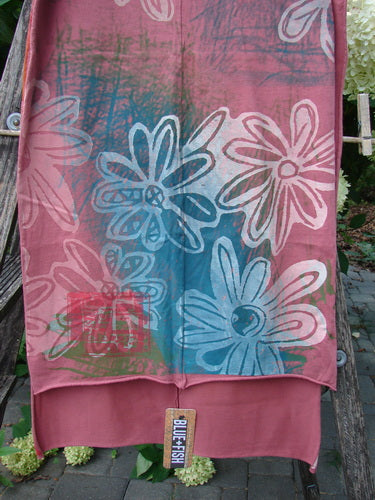 Barclay NWT Wide Sectional Scarf Daisy Desert Rose OSFA, featuring pink and turquoise tones with white daisy patterns, draped over wood. The lightweight organic cotton scarf shows unfinished rolled edges and a vertical seam.