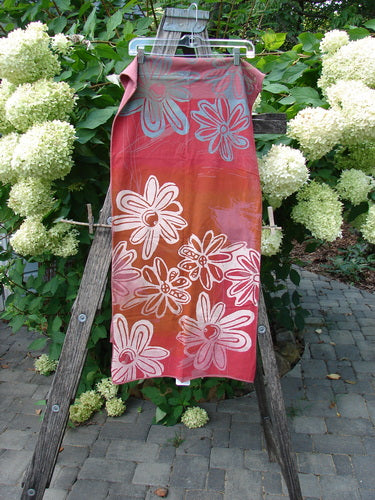 Barclay NWT Wide Sectional Scarf Daisy Desert Rose OSFA displayed in a garden setting, showcasing its painted daisy theme on medium-weight organic cotton, draped over a wooden ladder.