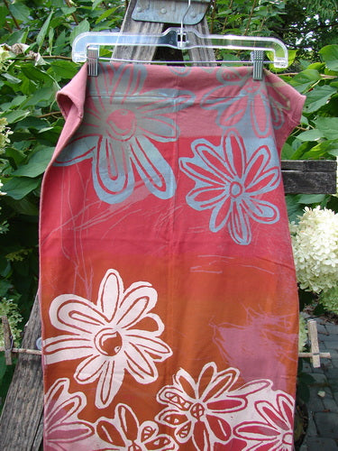 Barclay NWT Wide Sectional Scarf Daisy Desert Rose OSFA displayed outdoors, featuring warm red-orange to pink hues with large white and pale blue daisy prints on organic cotton, perfect as a versatile shawl or scarf.