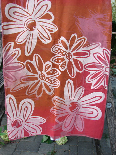 Barclay NWT Wide Sectional Scarf Daisy Desert Rose OSFA displayed over a wooden bench outdoors, featuring large, white-outlined daisies on a warm gradient background, showcasing an elegant drape and unfinished edges.