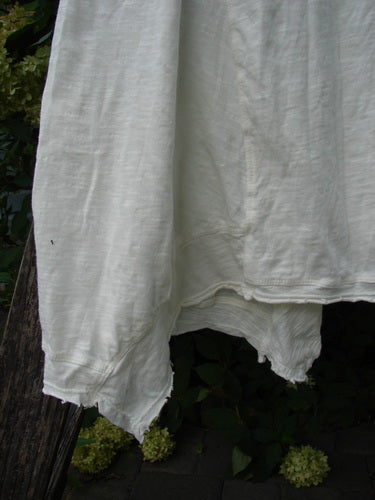 Magnolia Pearl NWT Cotton Paz Tank White OSFA hanging outdoors, showcasing its lightweight cotton jersey, raw tattered edges, varying hemline, and widening A-line shape, embodying vintage-inspired, expressive fashion.