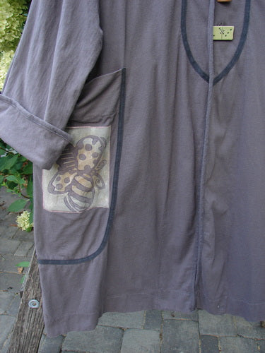 1998 Tiddly Winks Jacket Butterfly Madeira Size 2, featuring a loose-fitting grey smock with piped edges, a toggle closure, and a decorative appliqué on the pocket, represents vintage Blue Fish Clothing's creative individuality.