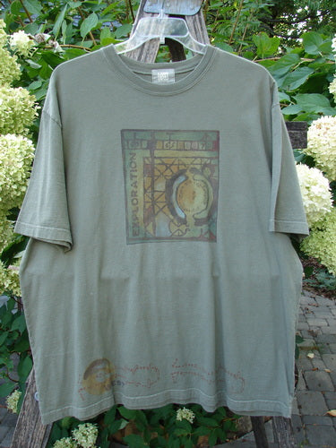 2000 Short Sleeved Tee Celtic Exploration Park Size 2 displayed outdoors; features a stylized globe graphic, exploration theme, and Celtic design on organic cotton with drop shoulders and thicker ribbed neckline.