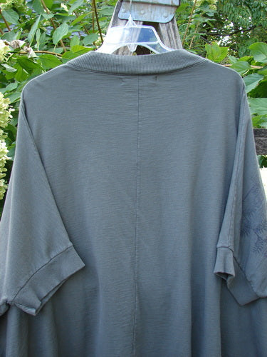 Barclay Slub Dolman Shirttail Pocket Jacket Fern Green Army Size 0 displayed outdoors, showcasing its textured organic cotton, dolman drop shoulders, and shirttail hemline on a hanger against a leafy backdrop.