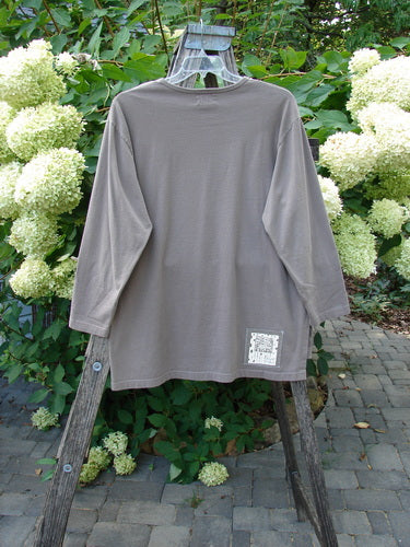 1999 Long Sleeved Vented Tee Orchid Sprig Shale Size 1 displayed on a wooden stepladder, showcasing its thicker ribbed neckline, sweet vented sides, and signature Blue Fish patch against a garden backdrop.