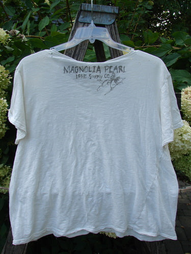 Magnolia Pearl NWT Cotton Europa V Neck Boyfriend Tee True White OSFA draped over a wooden trellis, showcasing hand-drawn text and illustration on the back, highlighting its unique, artistic detailing.
