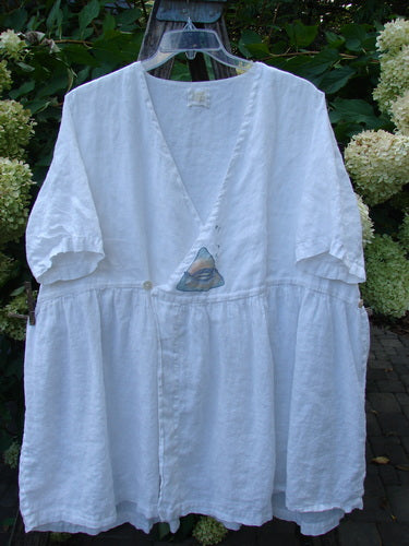 1999 Linen Adjustable Wrap Dress Fish White OSFA displayed outdoors on a hanger, featuring a V-neck with a button closure, gathered waist, short sleeves, and a flared hem, capturing Bluefishfinder.com's vintage essence.