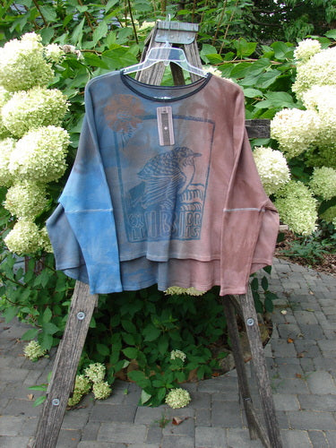Barclay NWT Thermal Crop Top Finch Mottled Bibbi Blue OSFA, displayed on a wooden ladder, features a bird graphic, scooped neckline, crop length, and fitted sleeves, embodying Bluefishfinder's unique, expressive style.