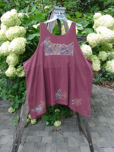 1994 Short Simple Smock Magic Music Beet Size 2: A loose-fit, sleeveless top with abstract motifs, featuring a rounded neckline, sectional panels, and varying hemline, displayed on a hanger against a patio backdrop.