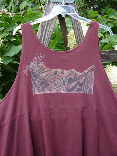 1994 Short Simple Smock Magic Music Beet Size 2 hanging outdoors, showcasing a maroon sleeveless design with a silvery tribal print and Magic script, featuring a rounded neckline and varying hemline.