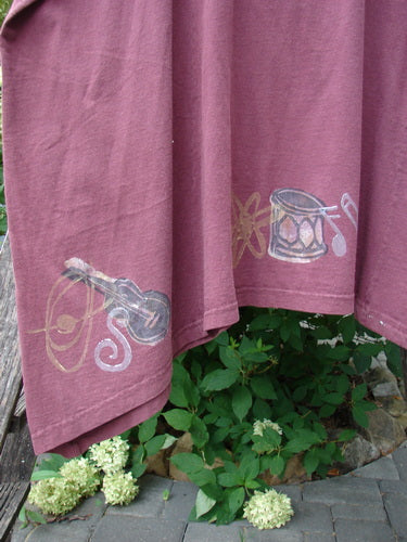 1994 Short Simple Smock Magic Music Beet Size 2 features hand-painted musical instruments along the hem, showcasing a lute, treble clef, and drum, hanging gracefully above a garden setting.