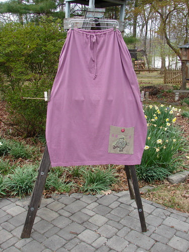 1997 Big Pocket Skirt Abstracts Crocus Size 1 displayed on a rack, featuring a unique bell-shaped bottom, a giant lower exterior pocket with a vintage Blue Fish button closure, and a drawstring waistline.