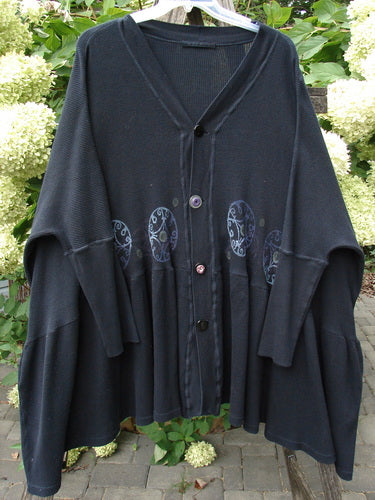 The 1997 Thermal Bungalow Jacket Celtic Medallion Cast Iron OSFA, featuring mismatched buttons, oversized sleeves, and a gathered hem with Celtic motifs, hangs outdoors, embodying Bluefishfinder's vintage, expressive style.