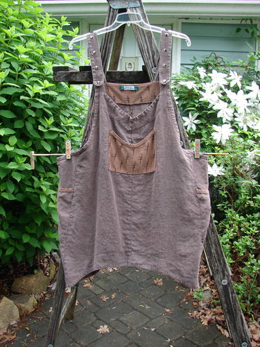 Barclay Linen Adjustable Snap Apron Jumper Playful Chirp Mocha Size 2 features adjustable shoulder straps, upper bib pocket, dual wrap pockets, and a playful birdie theme with varying hemlines.
