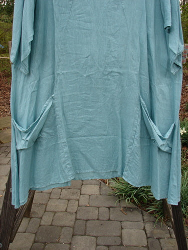 Barclay Linen Side Pocket Tab Tunic Dress Unpainted Mint Size 2 displayed on an outdoor clothesline, highlighting its lightweight linen fabric, oval neckline, and two drop-flop pockets.