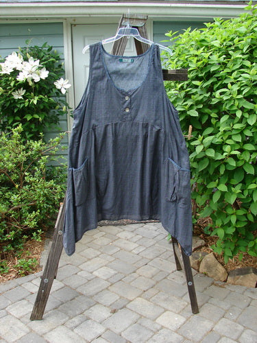 Barclay Tuesday's Pocket Prairie Dress Contrast Unpainted Grey Floral Size 2 displayed on a wooden rack, showcasing its detailed pleated pockets, shell buttons, and varying widening hemline.