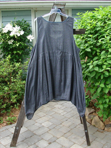 Barclay Tuesday's Pocket Prairie Dress on a clothes rack, showcasing its grey floral pattern, shell-like buttons, pleated pockets, and widening hemline.