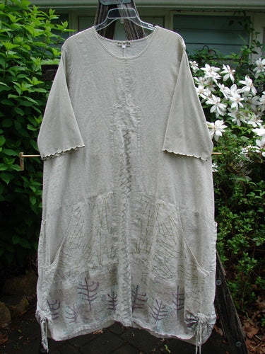 Barclay Linen Farmer Jen Dress Moon Path Flaxen Size 2 showcasing a sectional bodice, side pockets, paneled hem, drawcord sides, scooped neckline, and three-quarter sleeves with lettuce edgings, highlighting its unique A-line flair.