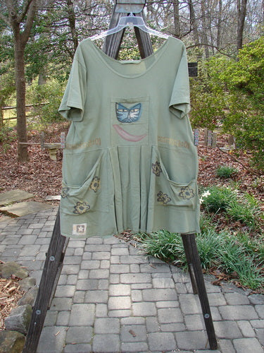 1995 PMU Blumenbeet Dress Kitty Kitty Marsh Size 1 featuring a painted cat face, front floppy pockets, vertical pleats, and unique lower patch, embodying vintage Blue Fish Clothing's creative and expressive style.