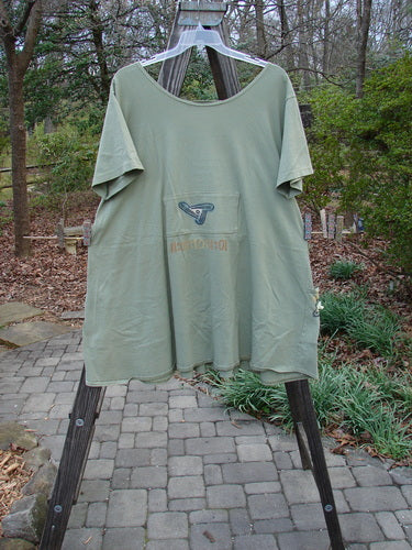 1995 PMU Blumenbeet Dress Kitty Kitty Marsh Size 1 displayed on a wooden rack, featuring a wider neckline, front and rear painted pockets, vertical center pleats, and a swingy lower hem.