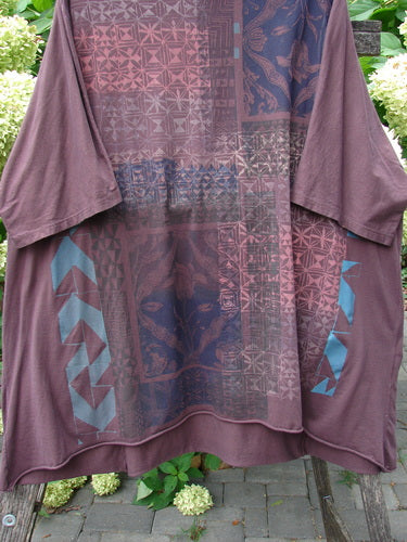 Barclay Art Tee Grid Flower Lower Lily Red Plum OSFA displayed on a wooden bench. The tunic features abstract patterns, three-quarter sleeves, a rounded neckline, and a varying hemline, embodying creative individuality.