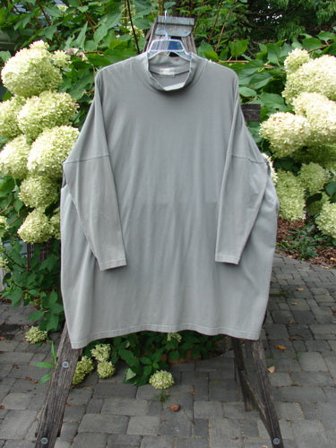 1999 Cotton Lycra Square Mock Pullover Unpainted Grey Stone Size 2, featuring an oversized, tunic-style design with dolman drop shoulders and a mock turtleneck, displayed on a wooden ladder outdoors.
