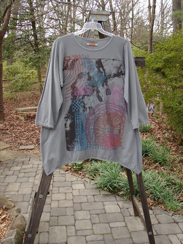 Barclay Long Sleeved Dip Side A Lined Tunic Daisy Logo Grey Storm Size 1 on a hanger outdoors, showcasing its rounded neckline, generous shape, and three-quarter sleeves made from organic cotton.