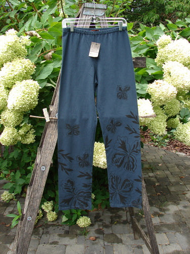 Barclay NWT Cotton Lycra Straight Pant Botanicals Lux Silhouette Size 1 hangs on a wooden ladder, showcasing a hibiscus-style floral pattern. The pants feature a full elastic waistband and wide lower legs.