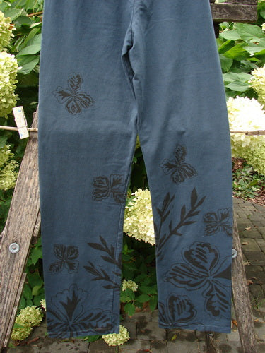 Barclay NWT Cotton Lycra Straight Pant Botanicals Lux Silhouette Size 1 displayed on a wooden rack, featuring a black floral and leaf motif concentrated on the lower legs, with a forgiving fit.