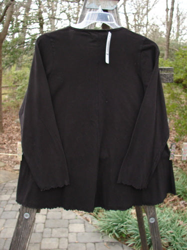 Barclay NWT Long Sleeved Cafe Tee Subtle Sun Frenchtown Black Cherry Size 1 displayed on a wooden rack, showcasing its rounded neckline, cozy long sleeves, and swinging A-line shape with curled edgings.