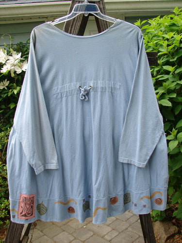 1993 Modernismo Cardigan Koi Periwinkle OSFA on a clothes rack, featuring rear shoulder pleats, old-time buttons, and drop-shaped kangaroo pockets.