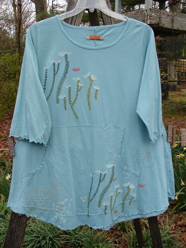 Barclay Three Quarter Sleeved Cafe Pocket Top Long Stem Dusty Aqua Size 1, featuring floral patterns, a feminine neckline, three-quarter sleeves, double side entry kangaroo pocket, and curly edgings.