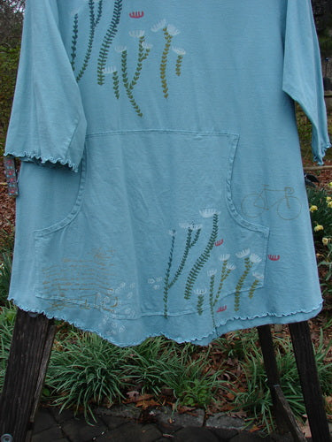 Barclay Three Quarter Sleeved Cafe Pocket Top in Dusty Aqua, featuring long stem flower design, A-line tunic shape, rounded hem, and three-quarter sleeves.