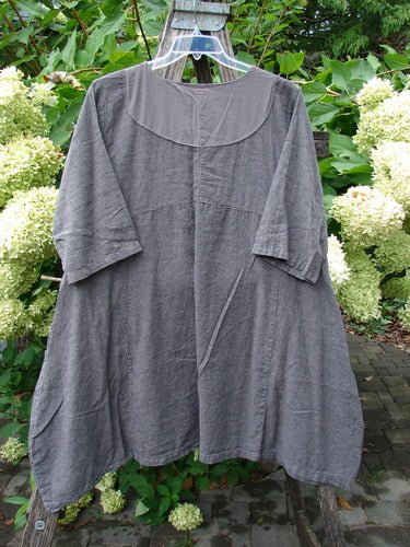 Barclay Linen Cross Over Urchin Pocket Dress Stripe Fig Size 1 features a loose, mid-length design with ¾ sleeves and a scooped neckline, displayed outdoors against lush greenery and white hydrangeas.