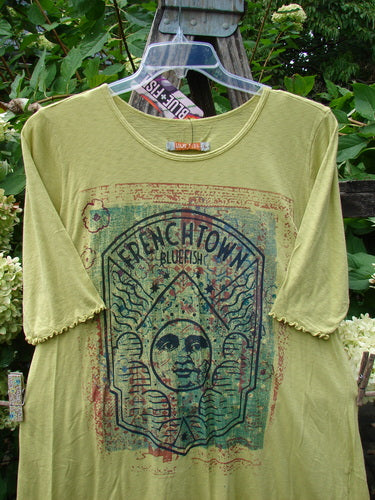 Barclay NWT Modal Slub Simple Tee Frenchtown Sun Gal Citron Size 1 features a distressed graphic with a stylized face and wavy lines, hung outdoors on a clear hanger against foliage.