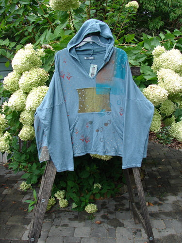 Barclay NWT Fleece Modal Hip To Be Square Hoodie Rain Flower Sea OSFA hangs on a garden ladder, showcasing its abstract print and cozy design, ideal for expressing individuality with comfort.