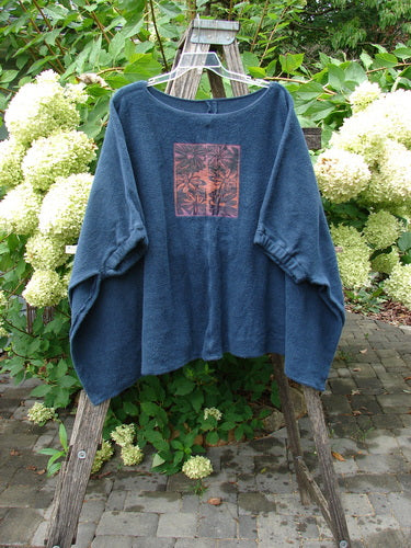 Barclay Celtic Moss Patched Poncho Single Six Daisy Ink Blue OSFA features an oversized, smock-style top with elbow-length sleeves and a square graphic print, draped over a ladder outdoors.
