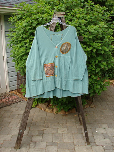 1993 PMU Patched Modernismo Cardigan in Grey Green. A green shirt with patches and whip stitched accents. Kangaroo front pockets and a banded hemline.