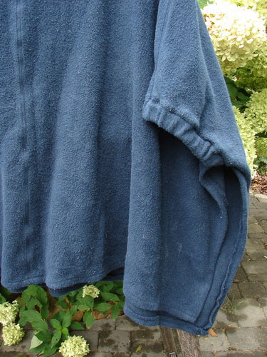 Barclay Celtic Moss Patched Poncho Single Six Daisy Ink Blue OSFA displayed outdoors, showcasing its open sides and gathered sleeves, emphasizing the cozy, plush texture of the Sherpa fleece fabric.
