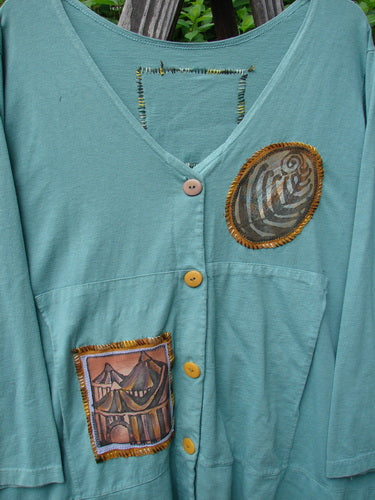1993 PMU Patched Modernismo Cardigan: blue shirt with tent and fabric design, whip stitched accents, kangaroo pockets, A-lined swing, drawcord back, oversized patches, banded hemline.