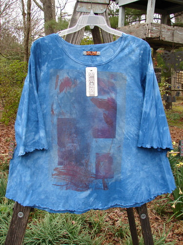 Barclay NWT Three Quarter Sleeved Cafe Tee Leaf Blend Mottled Clear Blue Sky Size 1 displayed on an outdoor hanger, showcasing its mid-weight organic cotton fabric and unique design features.